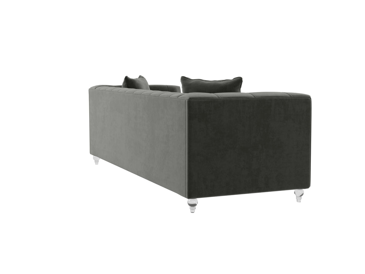 The Bea Velvet Tufted Sofa, shown at an angle on a white background, features a plush, dark gray velvet upholstery with a modern design and back cushions, complemented by clear cylindrical acrylic legs.