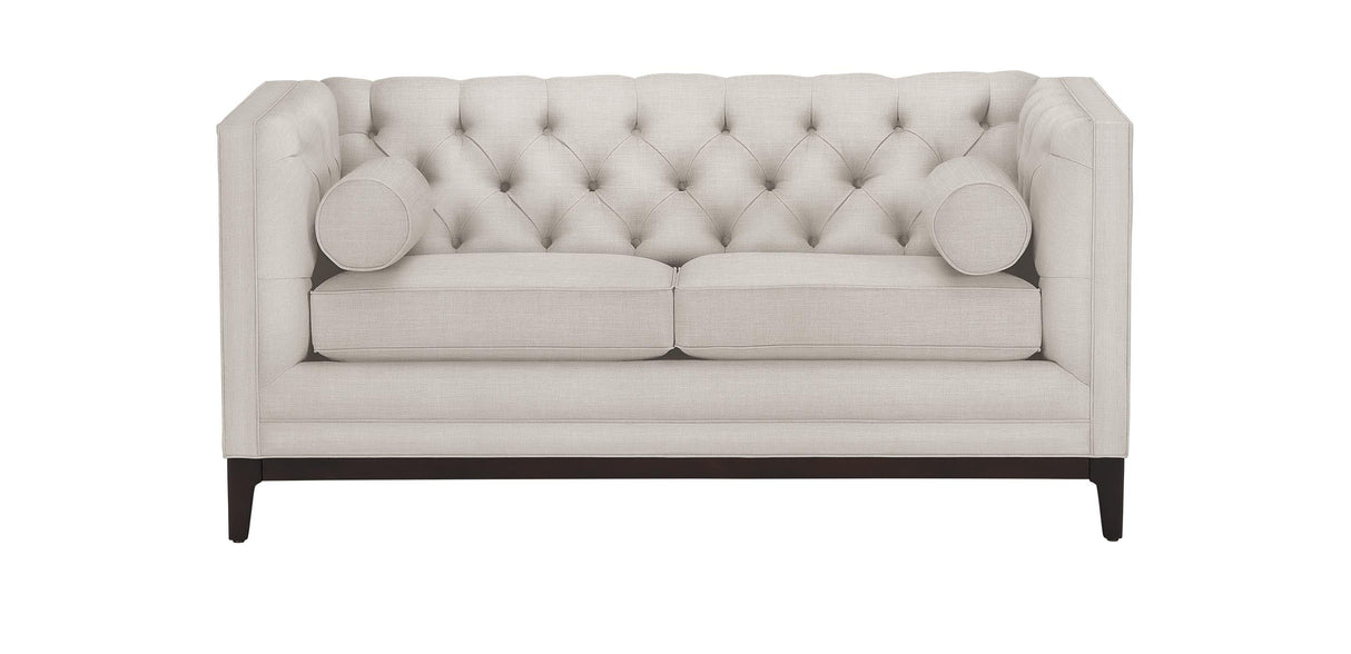 Introducing the Anderson Loveseat, a cream-colored, tufted piece with two matching round cushions. This loveseat is designed with a high back and arms and is supported by wooden legs.