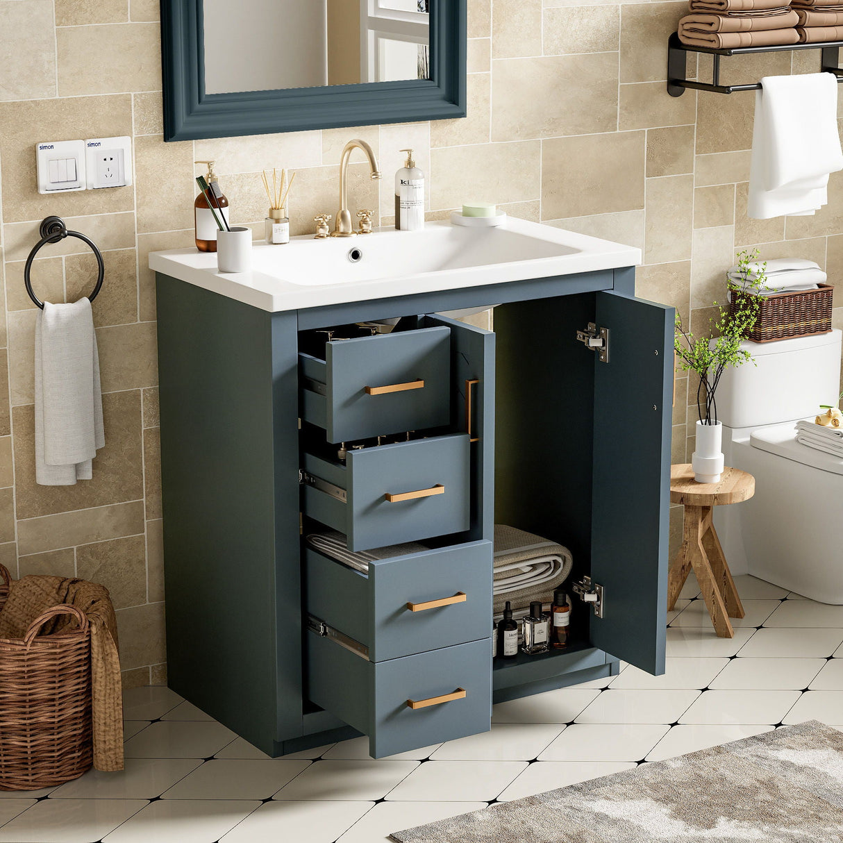 The Ceramic Sink Combo, a freestanding vanity set with a white countertop, sink, 3 drawers, and soft closing doors showcases an organized open storage cabinet. The decor includes tiled walls, a mirror above the sink, a towel rack with a towel, a wicker basket, and a small stool.