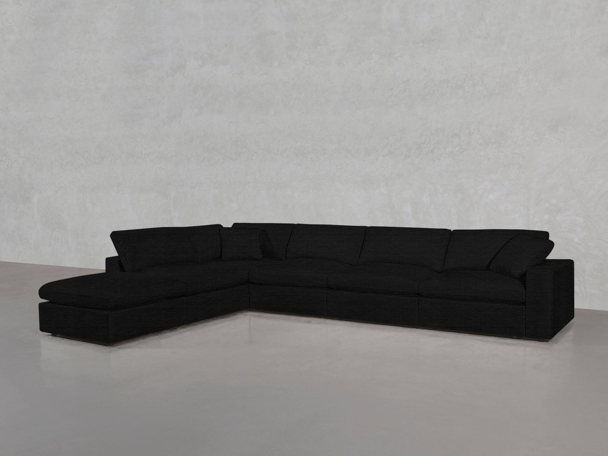 The 6-Seat Modular Corner Lounger Sectional in black features a left-facing chaise, set against a light gray textured wall and a smooth, reflective floor.