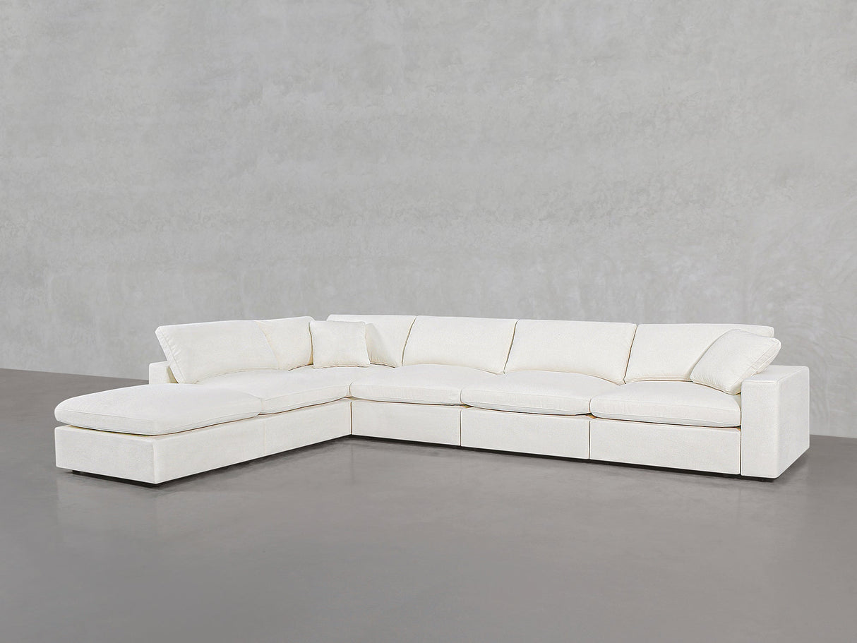 A modern 6-Seat Modular Corner Lounger Sectional in white with plush cushions and a left-side chaise, set in a minimalist room featuring light gray concrete flooring and walls.