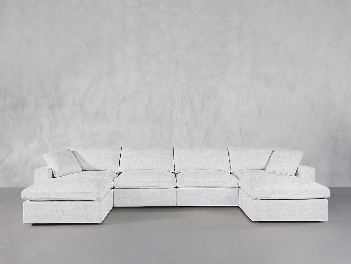 A 6-Seat Modular Double Chaise Sectional in light gray is displayed against a minimalist, light gray textured wall and floor.