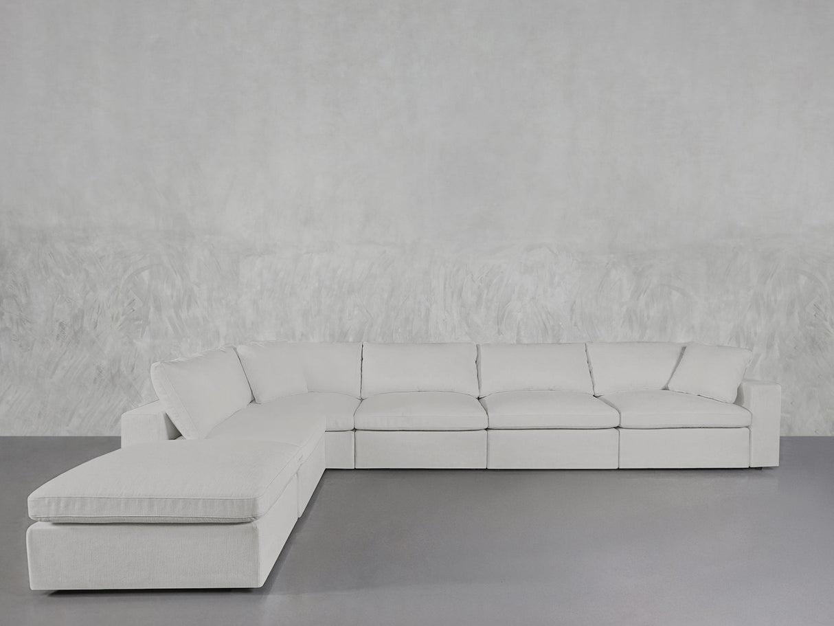 The 6-Seat Modular Corner Lounger Sectional, featuring clean lines and plush cushions in light gray, is placed against a textured light gray wall on a smooth gray floor.