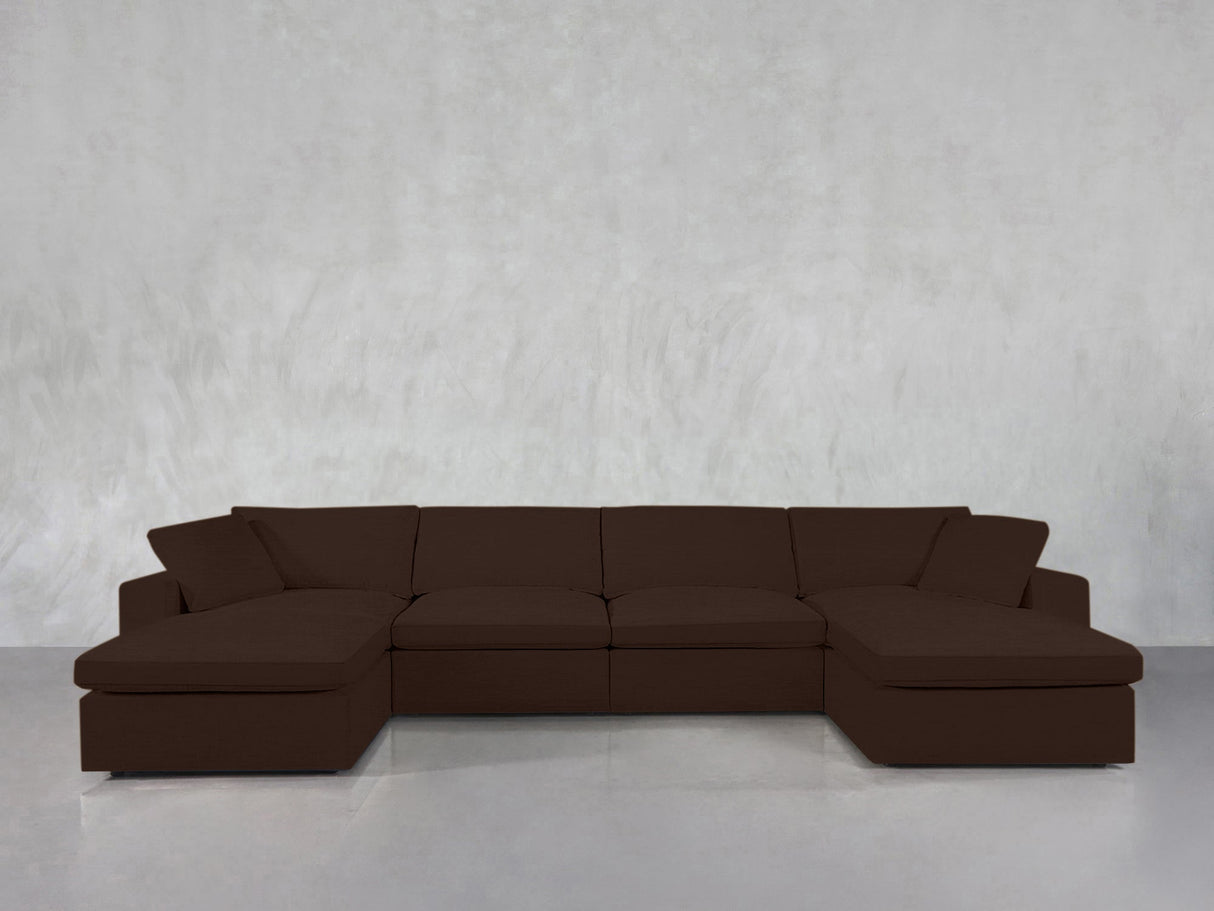 A 6-Seat Modular Double Chaise Sectional in dark brown sits against a plain light gray wall atop a shiny, light-colored floor.