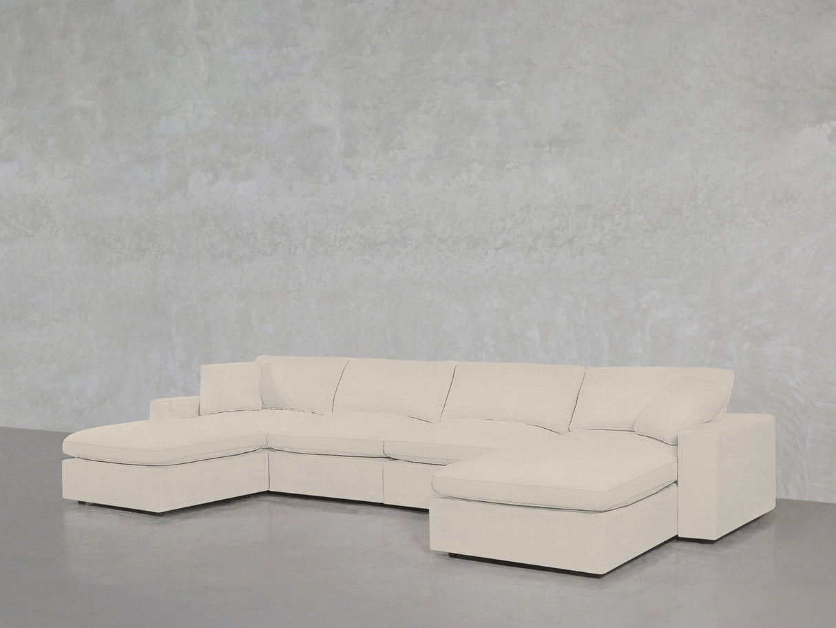 The 6-Seat Modular Double Chaise Sectional, featuring clean lines and plush cushions in light beige, is set against a gray textured wall and floor, with a chaise lounge on each end for modern comfort.
