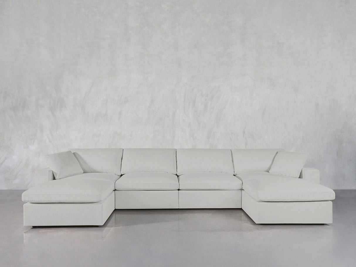 The 6-Seat Modular Double Chaise Sectional with clean lines and plush cushions is arranged in front of a light gray textured wall on a glossy floor.