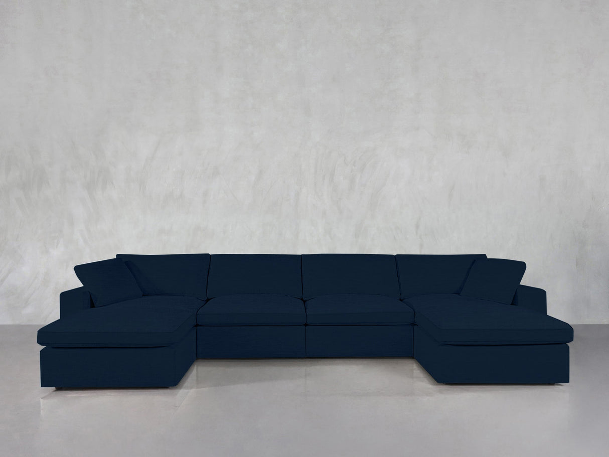 A 6-Seat Modular Double Chaise Sectional in dark blue is arranged against a plain light gray wall and a glossy gray floor.