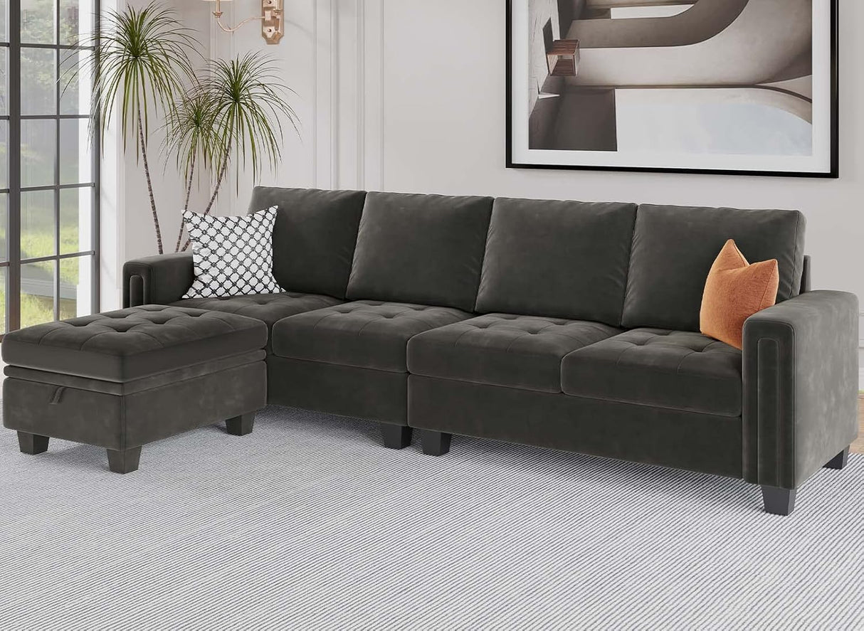 A modern living room featuring the Belffin Reversible Sectional Convertible Storage in dark green, paired with a matching ottoman on a light gray rug. The sectional is adorned with a black and white patterned pillow and an orange throw pillow for added color. A large plant completes the corner, while abstract art adorns the wall.