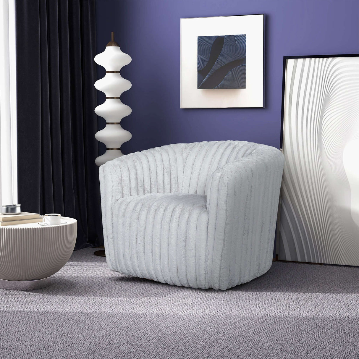 A modern room showcases a plush, light gray Mira - Modern Comfort Swivel Chair with vertical ridges, placed on a gray carpet near a sculptural lamp and abstract artwork on a deep blue wall. Nearby is a matching textured round coffee table.
