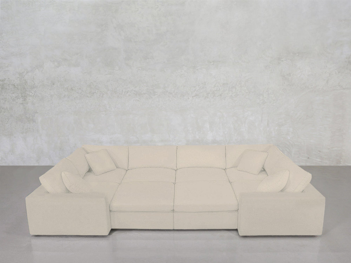 An 8-Seat Modular Closed Pit in beige, paired with four matching cushions, is arranged in a U-shape against a light gray textured wall and concrete floor.