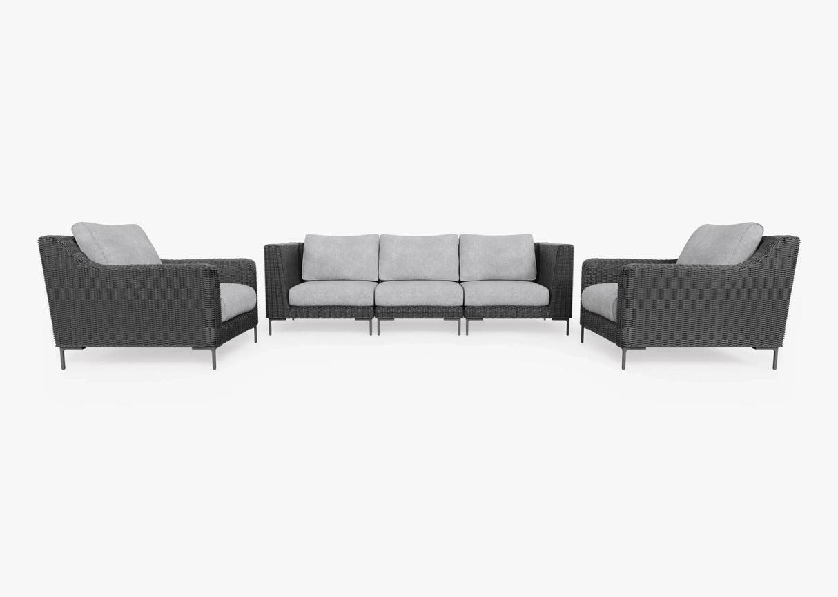 The Black Wicker Outdoor Sofa with Armchairs - Five Seat set offers a contemporary design, showcasing a three-seater sofa and two matching armchairs. These pieces feature sleek dark wicker frames paired with light gray cushions, all set against a pristine white background.