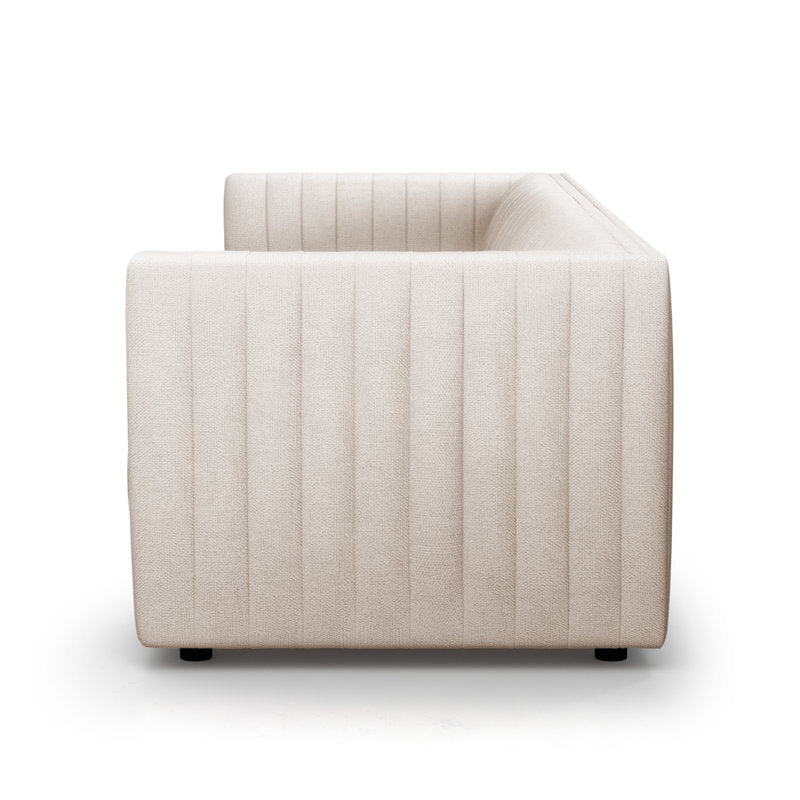 Side view of the Brandt 97'' Upholstered Sofa, showcasing its modern beige appearance and minimalist design. The upholstery is highlighted by vertical stitching, while it rests on small, dark legs against a plain white background to accentuate its clean lines.