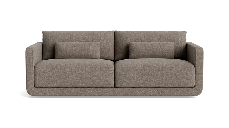 The Eva 85" Sofa is a modern design in brown, featuring two large cushions and two smaller rectangular pillows, set against a plain background.