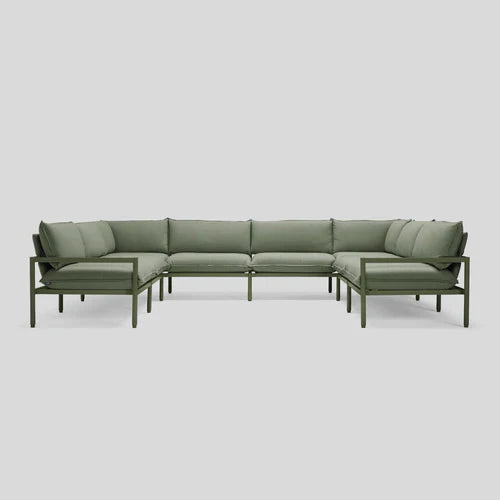 The Terra Sectional is a green L-shaped sofa featuring a sleek metal frame and plush cushions, set against a light gray background. Its minimalist design boasts straight lines and offers comfortable seating for multiple people.