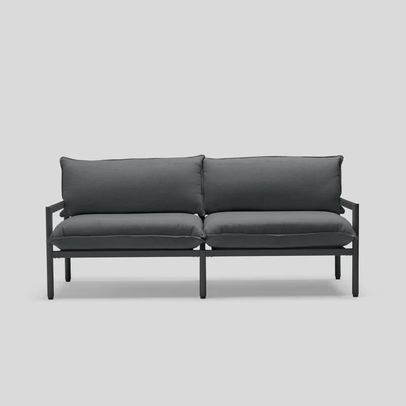 Introducing the Terra Loveseat: a minimalist outdoor sofa in dark gray, featuring a sleek metal frame and complemented by two cushioned seats and backrests, displayed against a simple light gray backdrop.