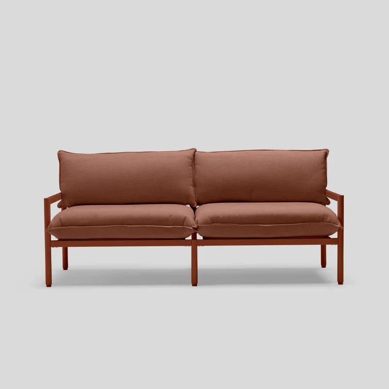 The Terra Loveseat, a minimalist piece with a wooden frame, is set against a gray backdrop. It features two seat cushions and two back cushions, providing a simple and modern design.