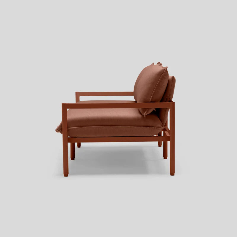 Side view of the Terra Loveseat showcasing a rust-colored metal frame and matching cushions on a light gray background, highlighting its minimalist design with a contemporary aesthetic.