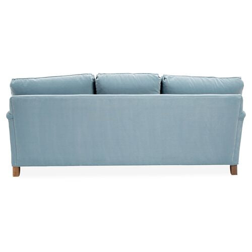Back view of the Brooke 6-Seat Sofa in light blue upholstery featuring three cushions and wooden legs, set against a white background.