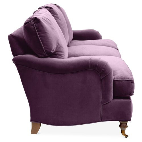 Side view of the Brooke 6-Seat Sofa, showcasing its stylish purple design with plush cushions and curved armrests. This sofa is complemented by turned wooden legs, which add a classic touch to its modern aesthetic.