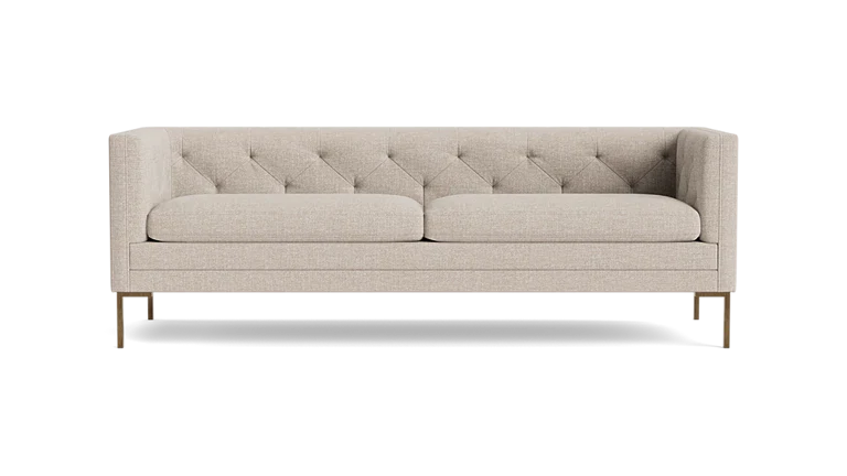 The Sit Tight 90" Sofa, featuring a beige tufted design with two cushions, is showcased against a solid black backdrop. Its minimalist aesthetic and wooden legs blend elegance with simplicity.