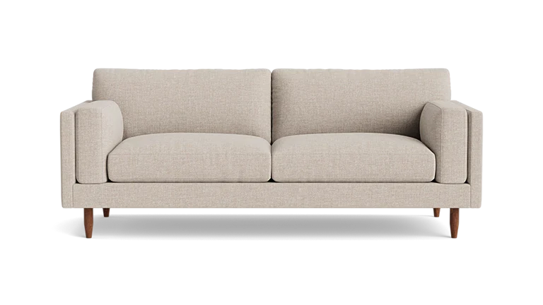 Introducing the "Skinny Fat 85" Sofa Standard Depth": A beige, modern sofa featuring two large cushions and wooden legs, elegantly set against a plain background. This minimalist masterpiece offers a cozy and stylish seating experience.
