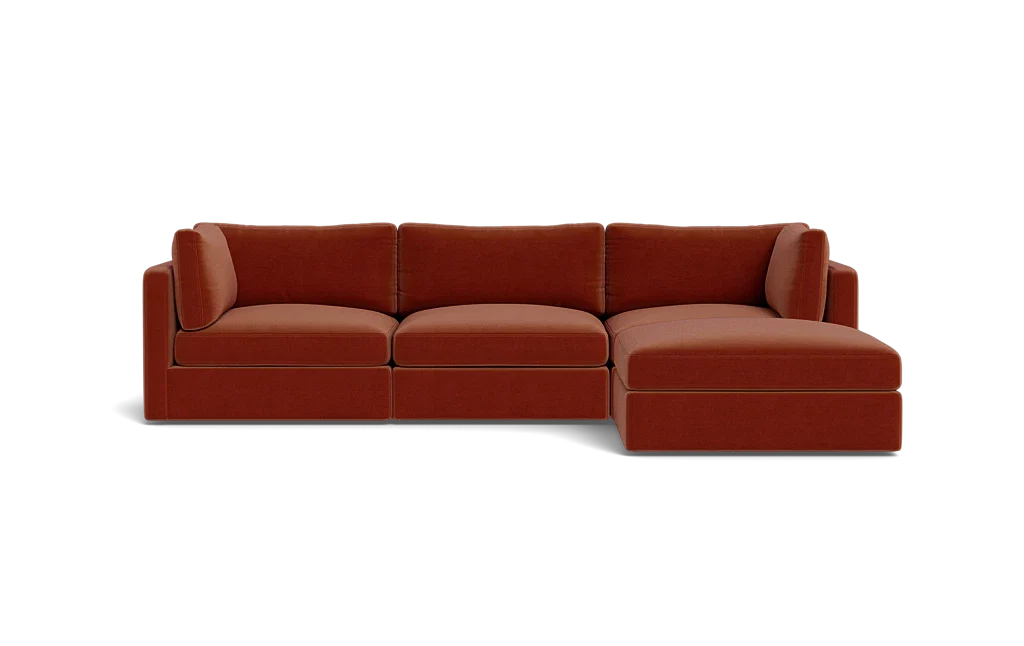 A contemporary Tatum Modular 3 Seat Chaise 106" Sectional showcasing clean lines, adorned with deep orange cushions, set against a simple black backdrop, and offering plush seating.