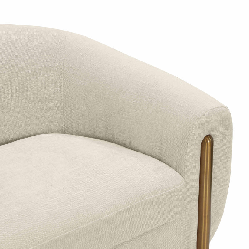 A close-up of the Lina Sofa by Inspire Me! Home Decor, showcasing its modern light beige upholstery with either wood or brass armrest supports. The fabric boasts a subtle texture, and the sofa features a rounded backrest for a sleek, contemporary design.