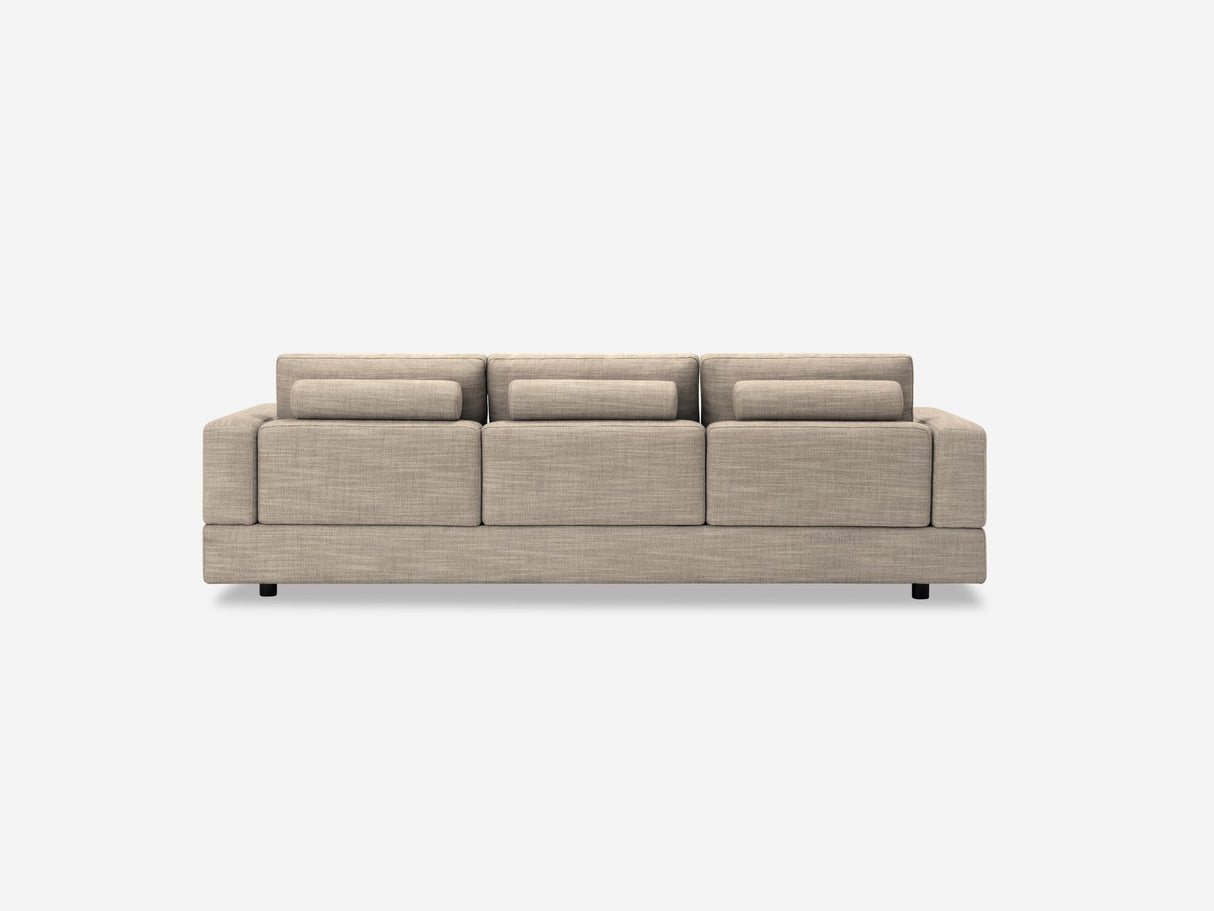A beige Stage Track Sofa with a minimalist design, featuring three seat cushions and three back cushions, set against a plain white background. Its low profile is complemented by simple, block-like armrests.