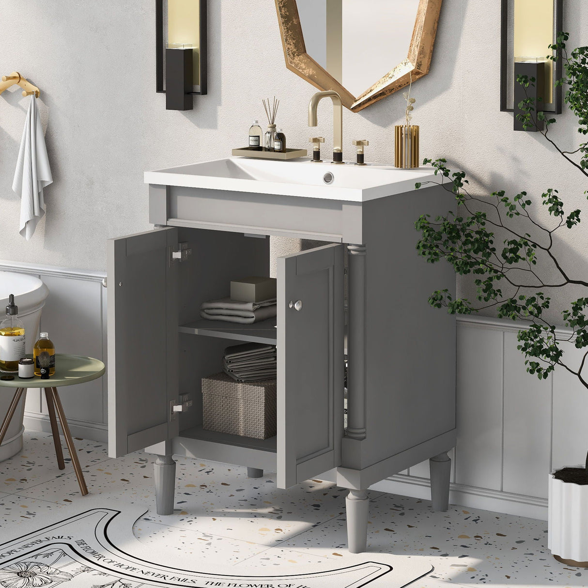 A compact gray bathroom vanity, the 2-tier modern storage cabinet houses towels and a basket. Features include a potted plant, wall-mounted lamps, and toiletries on the counter. A hexagonal mirror complements the space along with a patterned floor in the background.