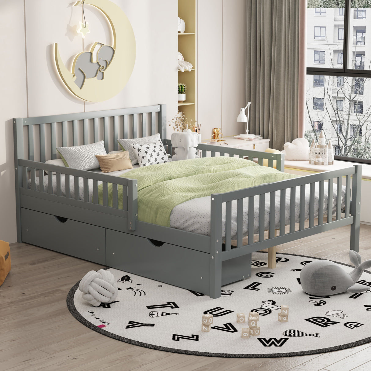 A child's bedroom includes a Platform Bed with guardrails, a green comforter, and under-bed storage drawers. A round alphabet rug lies on the floor amidst plush toys and blocks. The window view features a building and trees outside.