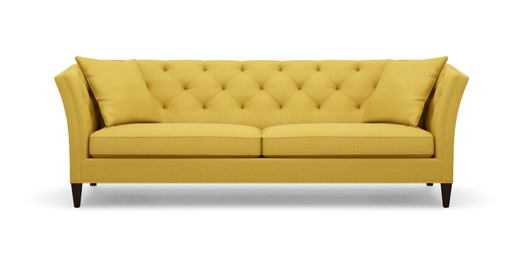 The Shelton 98" Sofa features a tufted backrest and two seat cushions in a mustard yellow color. It is designed with flair arms and rests on dark wooden legs.