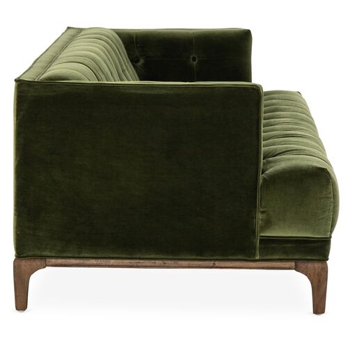 Side view of the Caledonia Sofa in Sapphire Olive Velvet featuring plush, tufted cushions. This sofa boasts a wooden base with short legs, presenting a stylish, modern design. The arm and backrest are padded with a textured finish, offering both comfort and elegance.