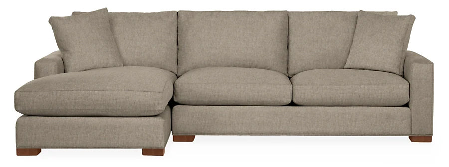 The Metro Sofas with Chaise is a beige sectional sofa featuring a left-side chaise lounge. It includes three seat cushions, three back cushions, and two matching throw pillows. The sofa is supported by wooden legs and showcases a simple, modern design.