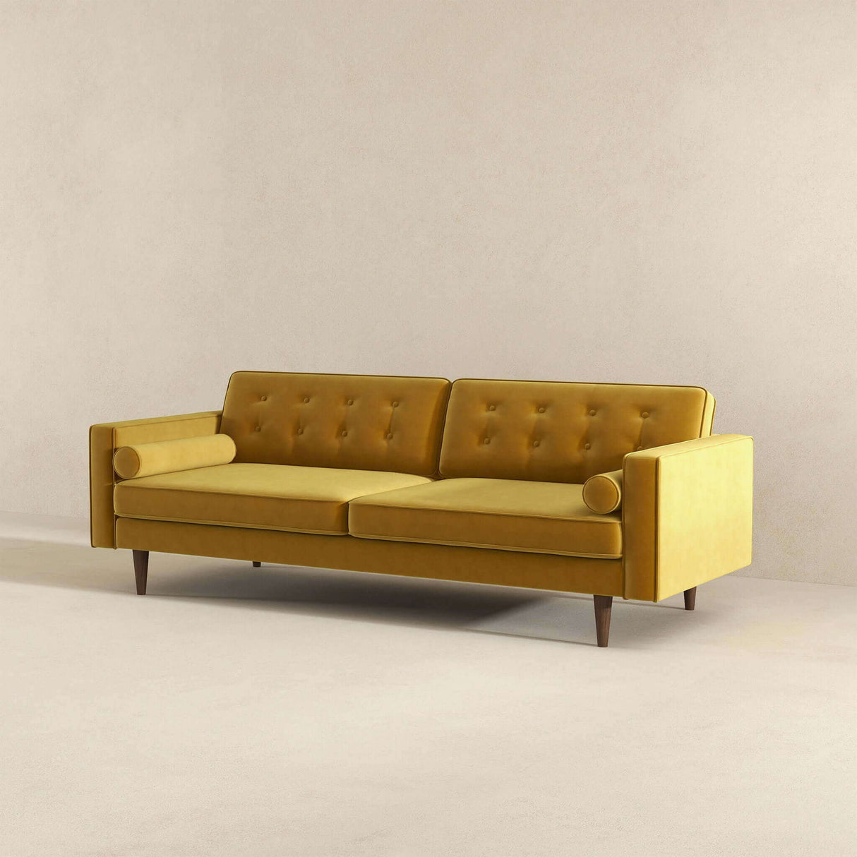 The Casey Mid Century Modern Sofa is a mustard yellow, featuring button-tufted back cushions, cylindrical bolster pillows, and wooden legs. It stands against a neutral-colored wall on a carpeted floor.