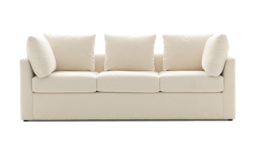 The Mitchell Gold + Bob Williams Dr Pitt Sofa is a modern, cream-colored, plush three-seater with clean lines and five matching cushions. Its minimalist design not only looks comfortable but also makes it ideal for a contemporary living room setting.