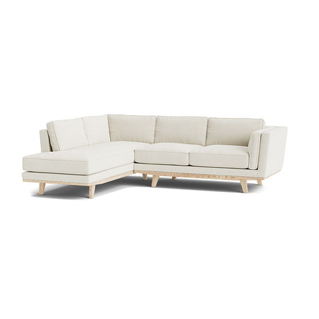 Introducing the Rio Sofa, a contemporary white sectional featuring sleek wooden legs. This design boasts a left-side chaise lounge and three seat cushions, providing a clean and minimalist aesthetic against a white backdrop.
