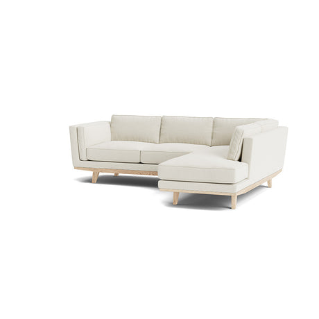 The Rio Sofa is a modern L-shaped beige sectional featuring wooden legs, plush cushions, and a minimalist design, all set against a plain white background.