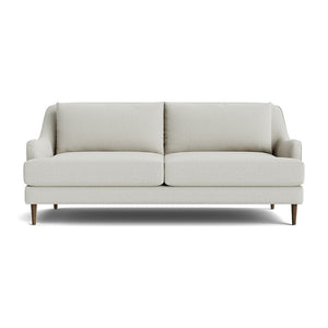 The Kaydan Sofa is a modern light gray piece with a minimalist design, featuring two seat cushions and two back cushions. It includes slightly angled armrests and stands on short, tapered wooden legs, set against a plain white background.