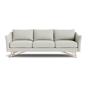 Introducing the Gio Sofa in Natural Latex, a contemporary piece upholstered in light gray fabric with three cushions and angled wooden legs. It boasts gently curved armrests and a sleek design, perfect for modern interiors.