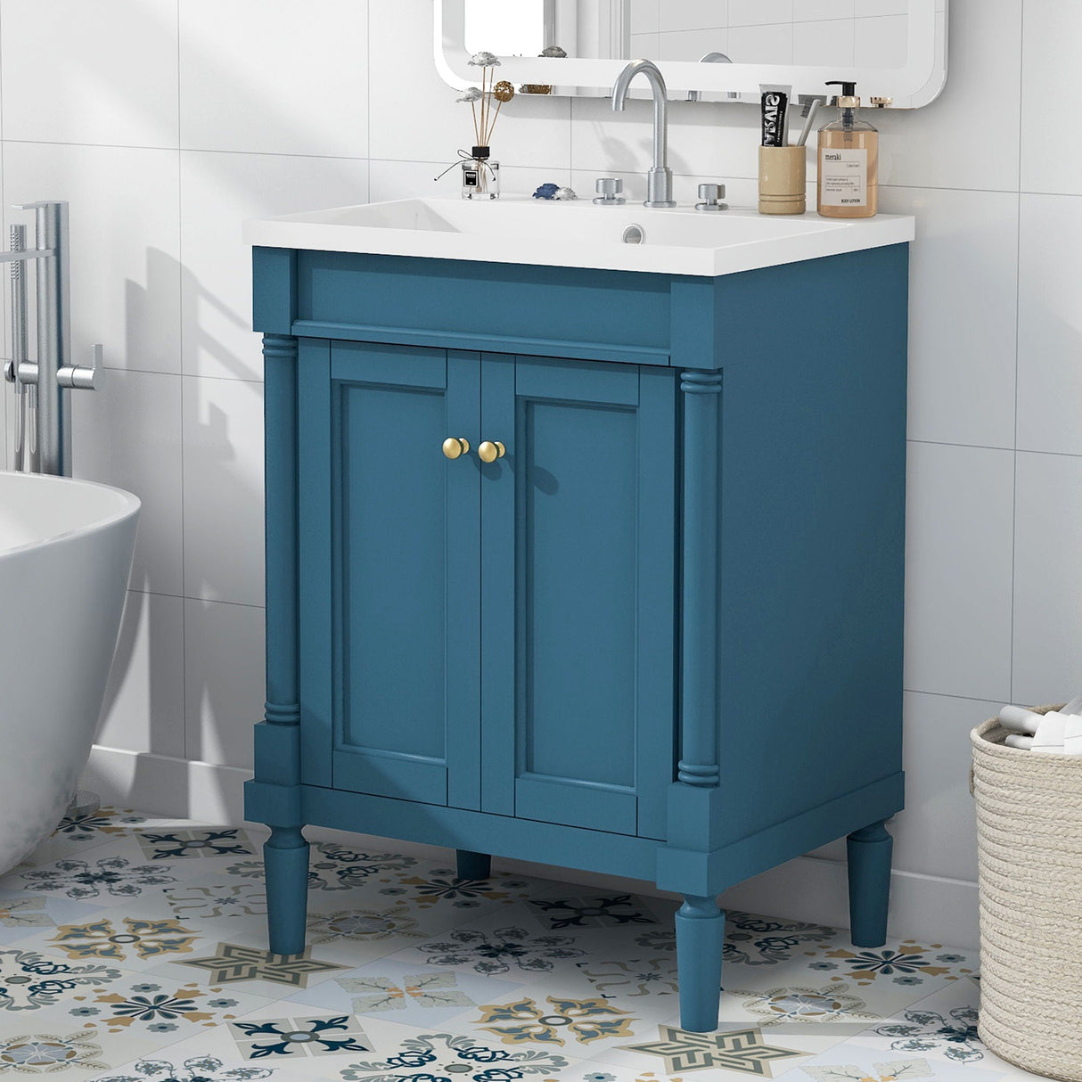 The Bathroom Vanity With Top Sink, a modern storage cabinet, features a blue design with two doors and gold knobs. It stands on patterned floor tiles with a white countertop and silver faucet. A rectangular mirror hangs above, while the room's walls are adorned with white tiles.