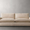 The Kipton 84" Deep Sofa, with its minimalist beige design and plush cushions, is positioned against a plain gray backdrop. Boasting a modern aesthetic with straight lines and soft fabric upholstery, it exudes a simple yet elegant look.