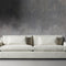 The Ashby Sofa, a minimalist off-white design featuring two large cushions, sits against a textured gray wall with concrete flooring.