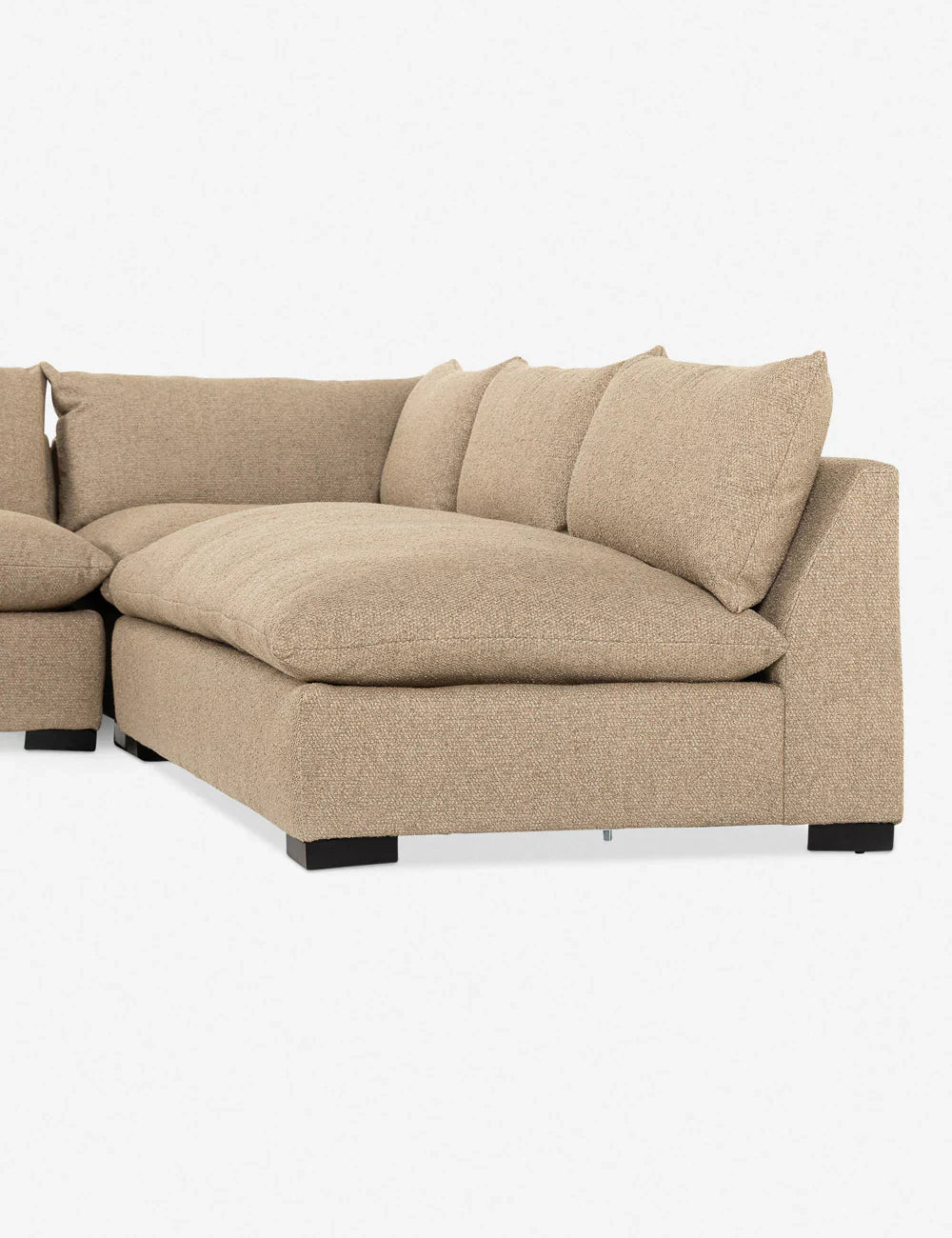 The Decima Sectional Sofa, featuring a modern design with thick cushions and a low backrest, is upholstered in beige fabric. It is positioned against a plain white background and stands on black wooden legs.
