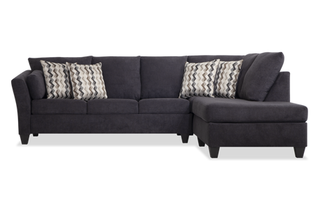 The Virgo Charcoal 119'' 2 Piece Chaise Sectional, with its dark gray hue and right-side chaise section, sits against a white background. It features a clean, modern design and includes five patterned throw pillows showcasing a chevron pattern.