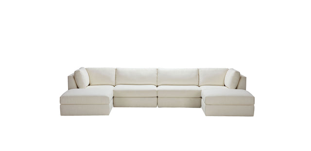 The Daydreamer Modular Six-Piece Sectional, a spacious L-shaped sofa in beige, features clean lines and plush cushions, beautifully contrasted against a plain white background.
