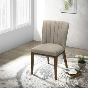 An Elmwood Stylish Dining Chair, beige and wooden-framed, sits on a circular patterned rug in a bright room. Sunlight pours through large windows, lighting up a book and potted plants nearby.