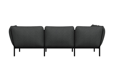 This Kumo Corner Sofa Left with Armrest showcases a stylish and modern design in dark gray, offering three seats and featuring sleek black legs for a minimalist look, viewed from the back.