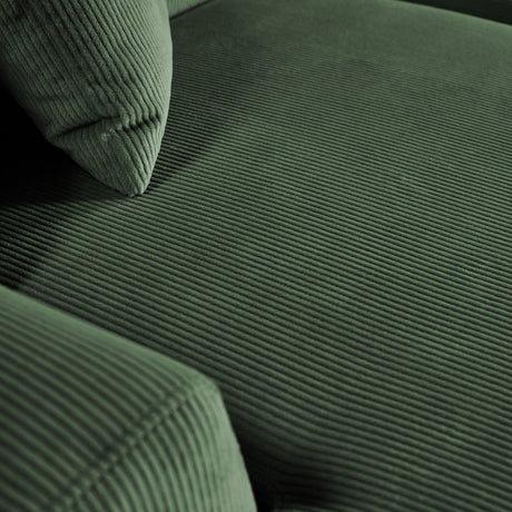 Close-up of the Mar - High-Quality Sectional Sofa in dark green, highlighting its textured, ribbed corduroy fabric. The visible cushion and armrest emphasize the plush and soft upholstery.