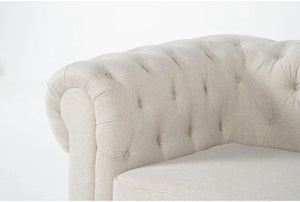 Close-up of the Elis Wheat 73 Inch Chesterfield Loveseat featuring beige tufted upholstery with a rolled armrest. The fabric exhibits a textured look, while the tufting enhances its classic appeal. The background is stark white.