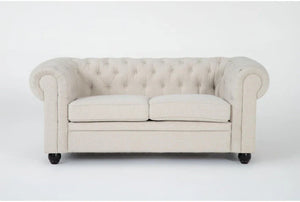The Elis Wheat 73 Inch Chesterfield Loveseat features a cream color with tufted upholstery, rolled arms, and two seat cushions. It is complemented by dark wooden legs and displayed against a plain white background.